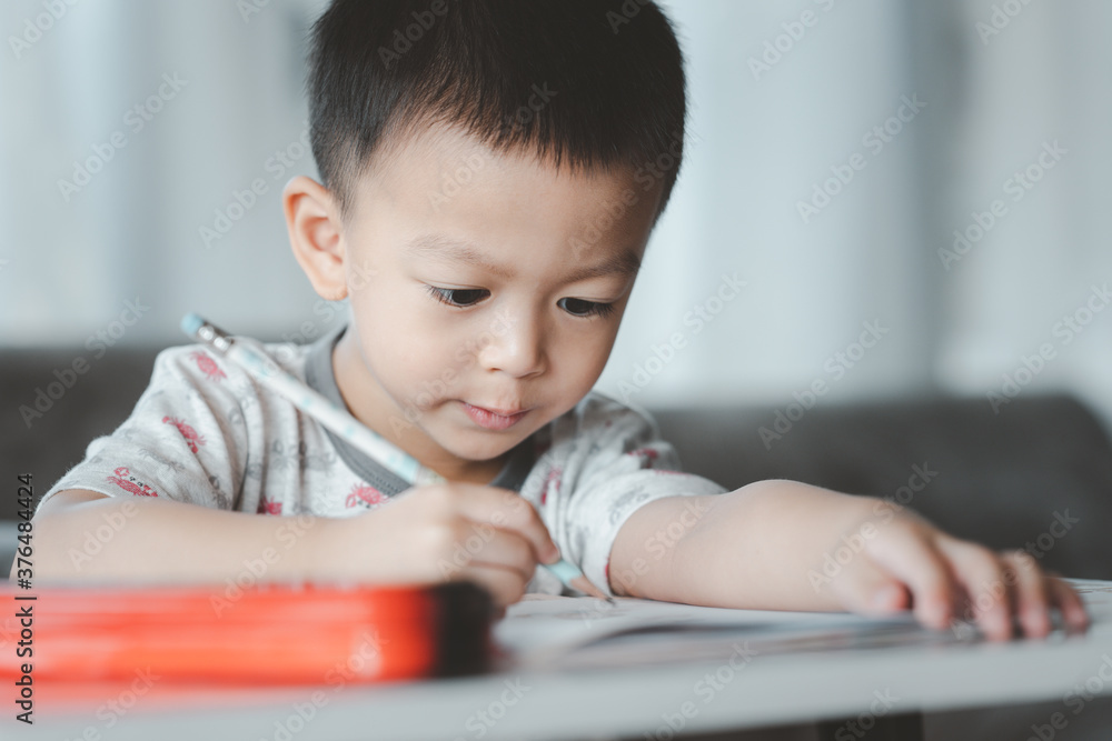 Asian Boy Doing homework with the intention. Child boy holding pencil writing, A boy drawing on white paper at the table,Elementary school and home schooling, Distance Education concept. Asian Boy Doing homework with the intention. Child boy holding pencil writing, A boy drawing on white paper at the table,Elementary school and home schooling, Distance Education concept.