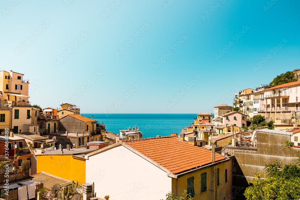 landscape view of Riomaggiore italian town on a summer day with sun. Cinque terre is an in italian landmark park with historic architecture
