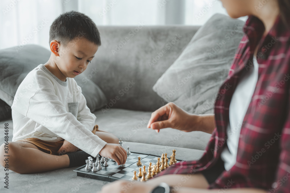 Family hobbies. son playing chess with mother at home. Little boy engaged in board game with his parent in room. Asian people. Family hobbies. son playing chess with mother at home. Little boy engaged in board game with his parent in room. Asian people.