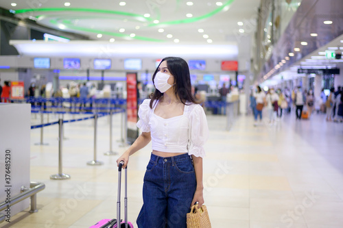 A traveller woman is wearing protective mask in International airport, travel under Covid-19 pandemic, safety travels, social distancing protocol, New normal travel concept © tonefotografia