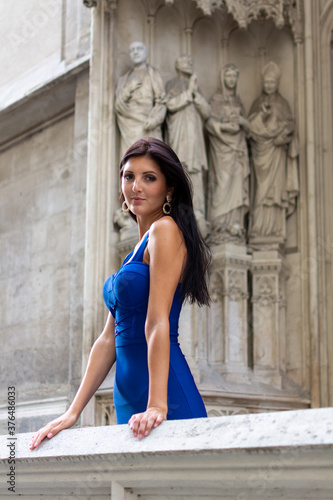 Young beautiful stylish girl in blue summer dress walking and posing in an old city center scene in Vienna, Austria