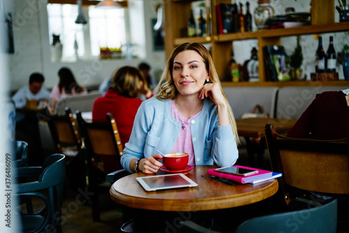 Delighted woman with cup of coffee in cafe