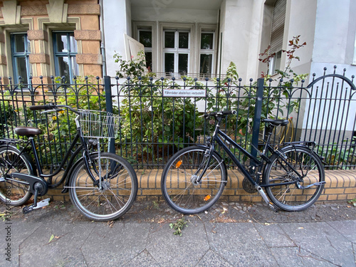 Fahrräder stehen an Zaun mit Schild 
