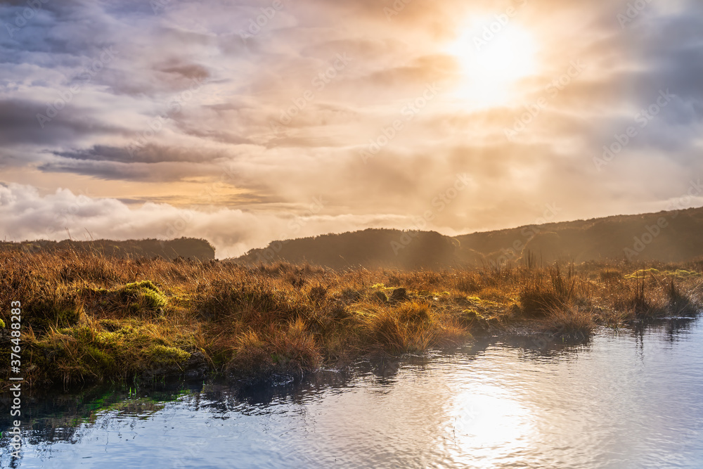 Fog, mist and dramatic sky over a swamp or bog with sun reflecting in a lake. Dramatic landscape of Wicklow mountains, Ireland