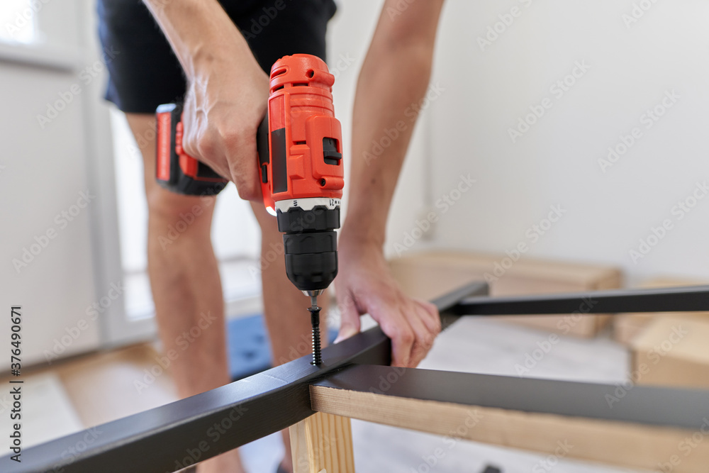 Young man assembling his furniture Young man assembling his furniture