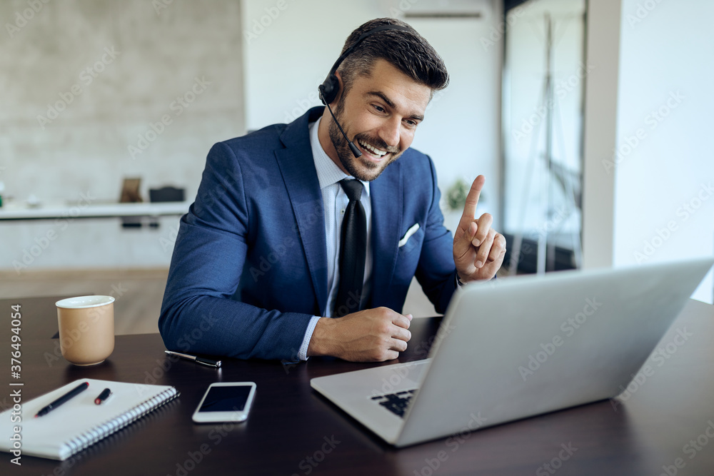 Happy businessman talking to someone via video call while working in the office. Happy businessman talking to someone via video call while working in the office.