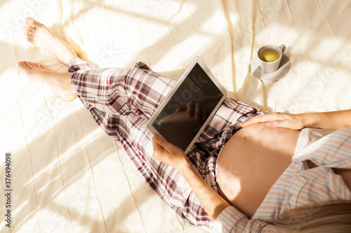 pregnant woman at home using digital tablet