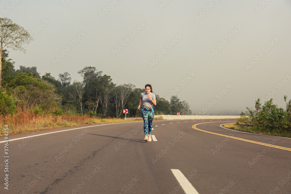 Woman running on the road. Jungle landscape. Concept of health and sport.