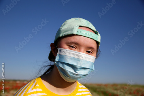 Girl with mask on her face on background on the flowers field © denys_kuvaiev