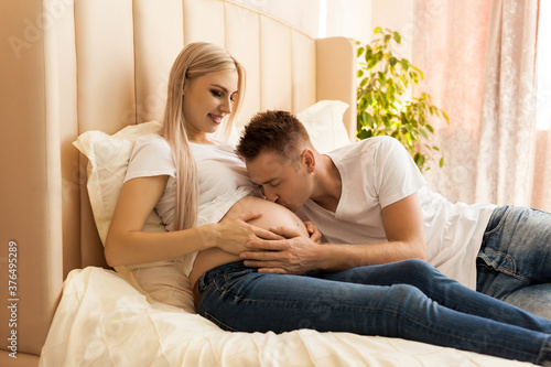 Husband kissing newborn through wife belly at home