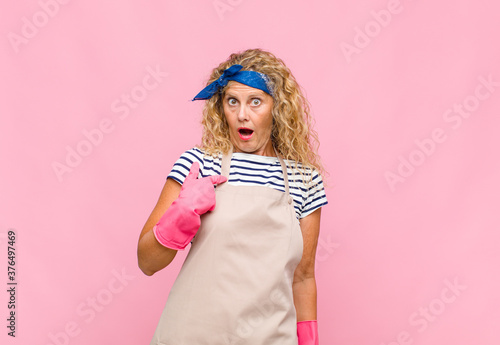 middle age womanlooking shocked and surprised with mouth wide open, pointing to self housekeeper concept photo