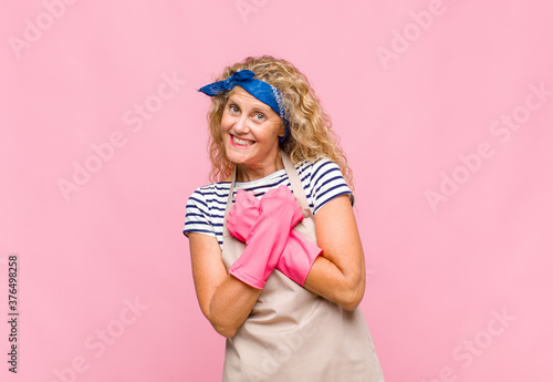 middle age womansmiling cheerfully and celebrating, with fists clenched and arms crossed, feeling happy and positive housekeeper concept photo