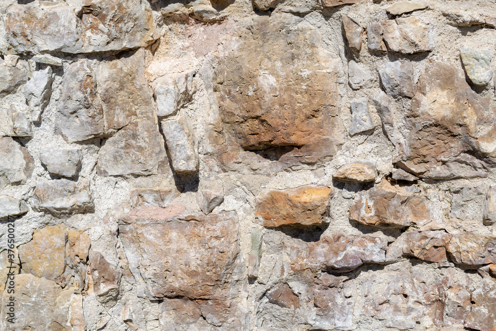 Naklejka premium Uneven, old, rough, irregular granite stone wall. Natural textured background.