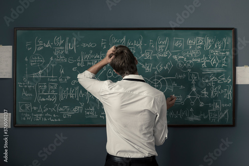 Obraz w ramie Mathematician solving problems and writing formulas on the chalkboard