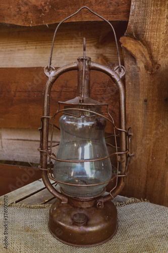 Old vintage and rusty green kerosene lamp on the wooden background. Decorative, retro lantern
