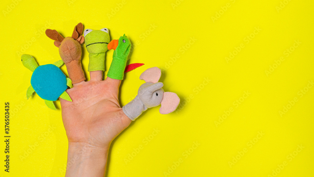 Fingers toys made of fabric on the hand on a yellow background banner with a place for text. Fingers Theatre. Fingers toys made of fabric on the hand on a yellow background banner with a place for text. Fingers Theatre.