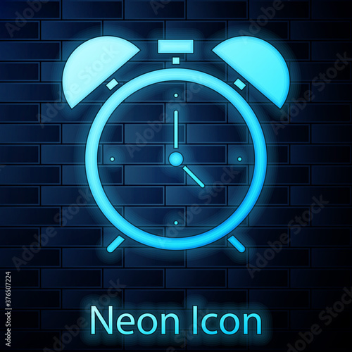 Glowing neon Alarm clock icon isolated on brick wall background. Wake up, get up concept. Time sign. Vector.