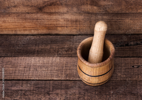 wooden mortar with pestle on brown wooden background