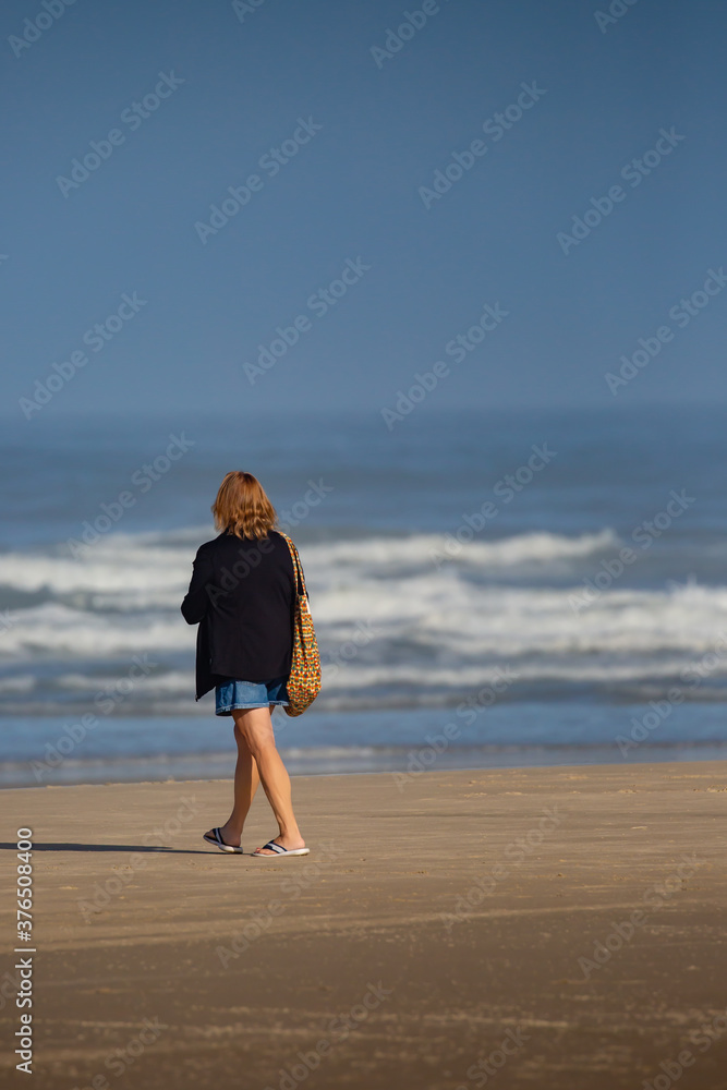 Woman walking on a beach next to the ocean in Oregon