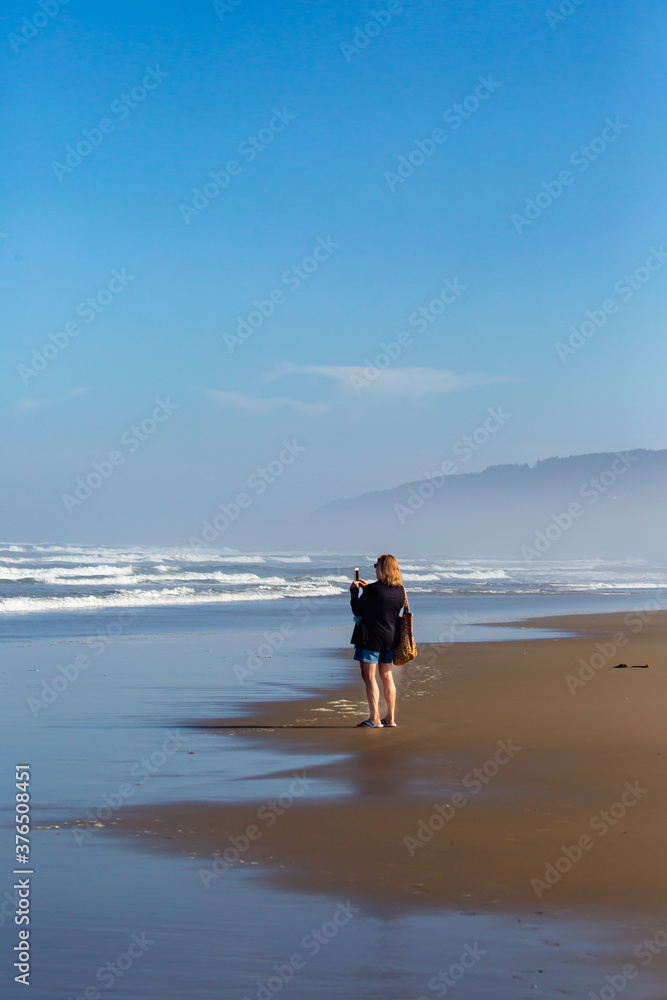 Woman taking photo of the pacific ocean in Oregon with her smartphone Woman taking photo of the pacific ocean in Oregon with her smartphone