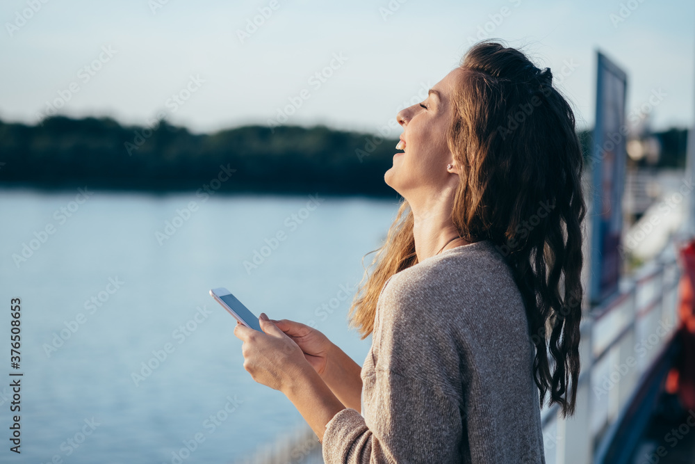Naklejka premium Smiling young woman looking in mobile phone