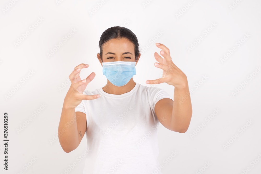 Young arab woman wearing medical mask standing over isolated white background Shouting frustrated with rage, hands trying to strangle, yelling mad. Young arab woman wearing medical mask standing over isolated white background Shouting frustrated with rage, hands trying to strangle, yelling mad.