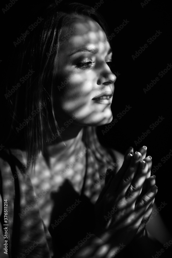 Beautiful woman confesses in the confessional, black and white. Praying woman, fine art portrait with interesting ligth and shadow pattern. Absolution.