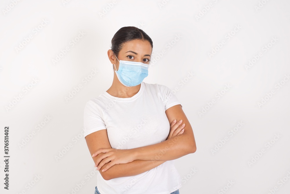 Young arab woman wearing medical mask standing over isolated white background happy face smiling with crossed arms looking at the camera. Positive person. Young arab woman wearing medical mask standing over isolated white background happy face smiling with crossed arms looking at the camera. Positive person.