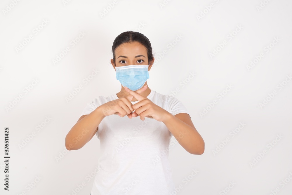 Young arab woman wearing medical mask standing over isolated white background Has rejection angry expression crossing fingers doing negative sign. Young arab woman wearing medical mask standing over isolated white background Has rejection angry expression crossing fingers doing negative sign.