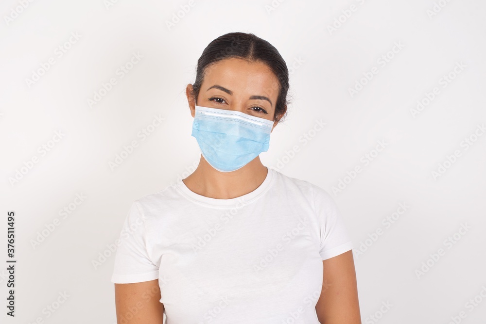 Young arab woman wearing medical mask standing over isolated white background with a happy and cool smile on face. Lucky person.