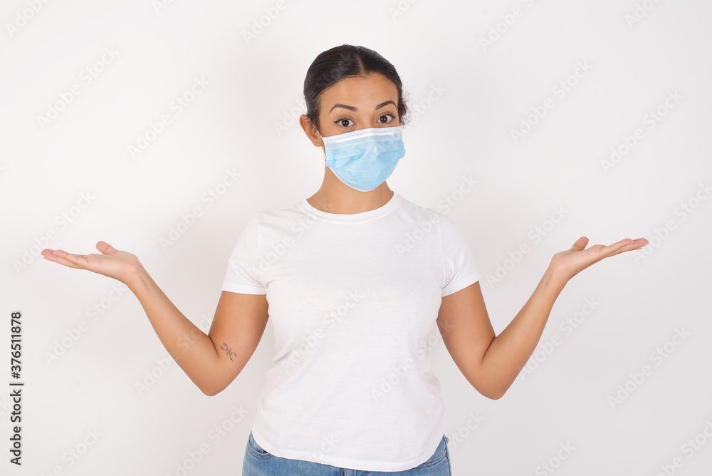 Cheerful cheery optimistic Young arab woman wearing medical mask standing over isolated white background holding two palms copy space Cheerful cheery optimistic Young arab woman wearing medical mask standing over isolated white background holding two palms copy space