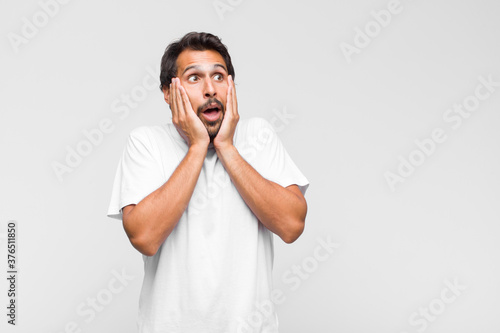 young latin handsome man feeling disgusted, holding nose to avoid smelling a foul and unpleasant stench