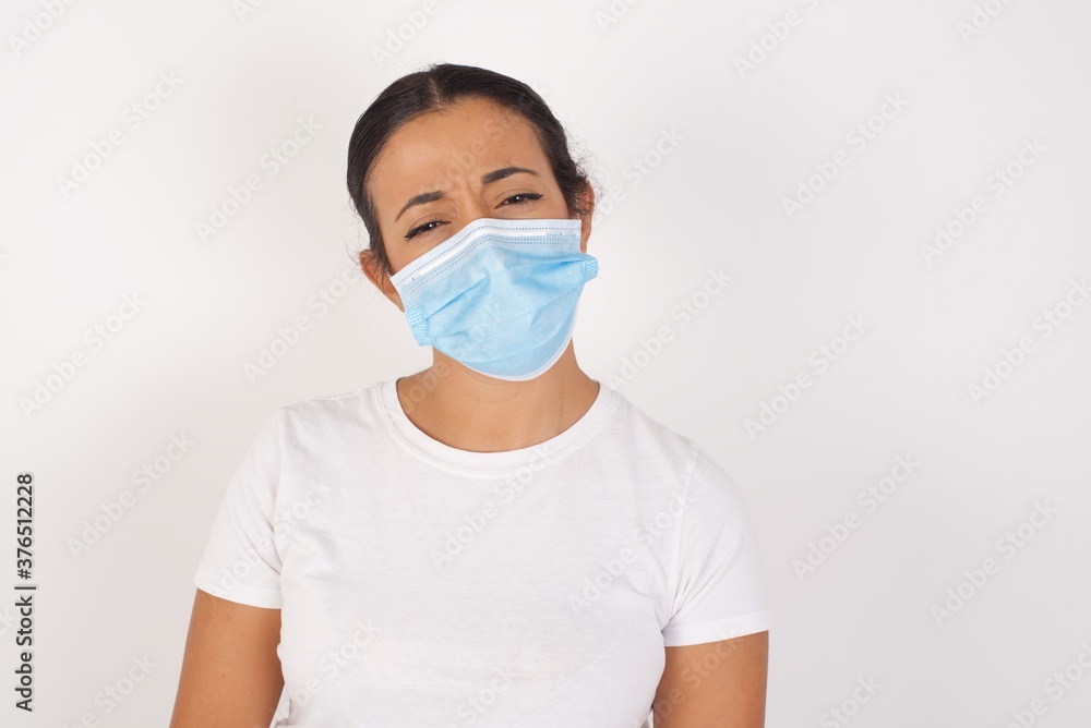 Portrait of displeased upset Young arab woman wearing medical mask standing . frowns face as going to cry, being discontent and unhappy as can't achieve goals,  Disappointed young man has troubles