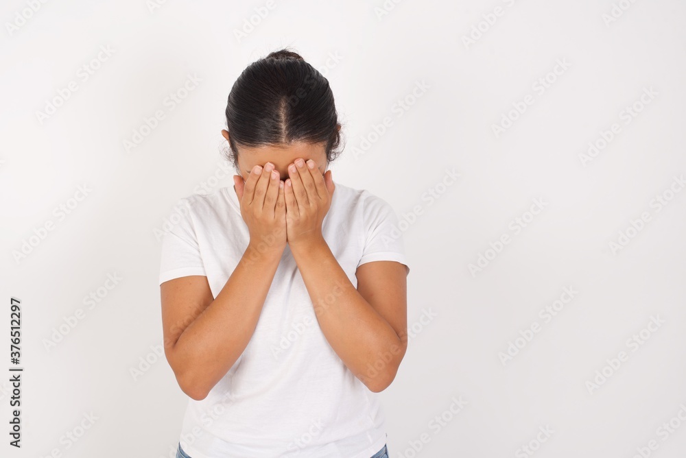 Young arab woman wearing medical mask standing over isolated white background covering her face with her hands, being devastated and crying. Sad concept Young arab woman wearing medical mask standing over isolated white background covering her face with her hands, being devastated and crying. Sad concept