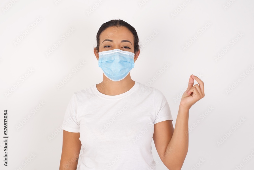 Young arab woman wearing medical mask standing over isolated white background pointing up with hand showing up seven fingers gesture in Chinese sign language QÄ«. Young arab woman wearing medical mask standing over isolated white background pointing up with hand showing up seven fingers gesture in Chinese sign language QÄ«.