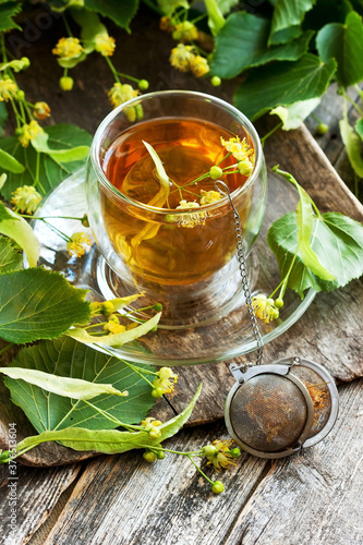 Cup of herbal tea with linden flowers on  old wooden table © amberto4ka