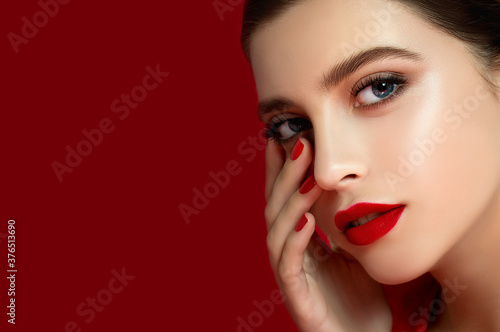 Portrait of beautiful young woman wearing red clothes with perfect young skin, red matt lips and nails.