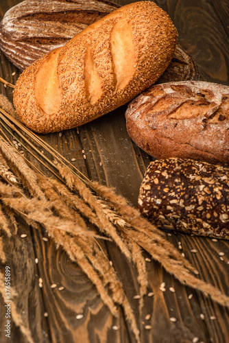 fresh baked bread loaves with spikelets on wooden surface