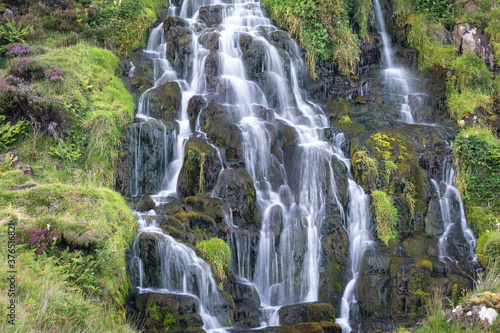 View of Bride Veil waterall on the Isle of Skye, Scotland. Beautiful collection of many smaller falls flowing in different directions. Fern and blooming heather around