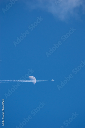 airplane crossing the moon in the sky