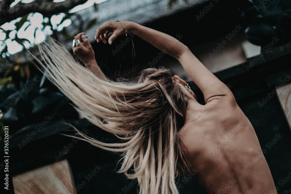 Naklejka premium Portrait of young model with boho accessories. Beautiful girl from the back tossing hair in air and enjoying fresh air in outdoor. Concept of hippie free lifestyle.