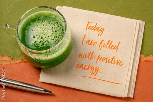 today I am filled with a positive energy - inspirational note on a napkin with a glass of fresh green cucumber juice, lifestyle and positivity concept photo