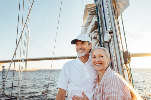Happy senior couple standing at mast. Two smiling people enjoying boat trip.