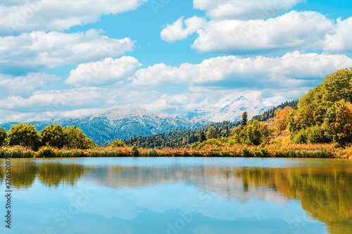 Fototapeta Naklejka Na Ścianę i Meble -  Autumn landscape. View of the lake and the autumn forest. Blue sky with clouds
