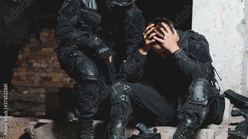 Ranger in black uniform supporting his partner after battle. Help in battle concept.