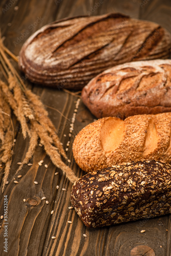 selective focus of fresh baked bread loaves with spikelets on wooden surface selective focus of fresh baked bread loaves with spikelets on wooden surface