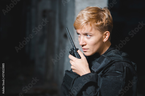 Young woman soldier in black uniform reporting on the radio