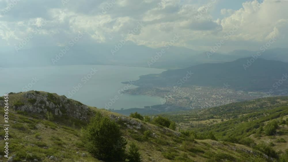 Aerial shot Ohrid Macedonia. Drone flying over the mountains with peaks and trees and in the background a lake and a city with houses and red roofs. Aerial shot Ohrid Macedonia. Drone flying over the mountains with peaks and trees and in the background a lake and a city with houses and red roofs.