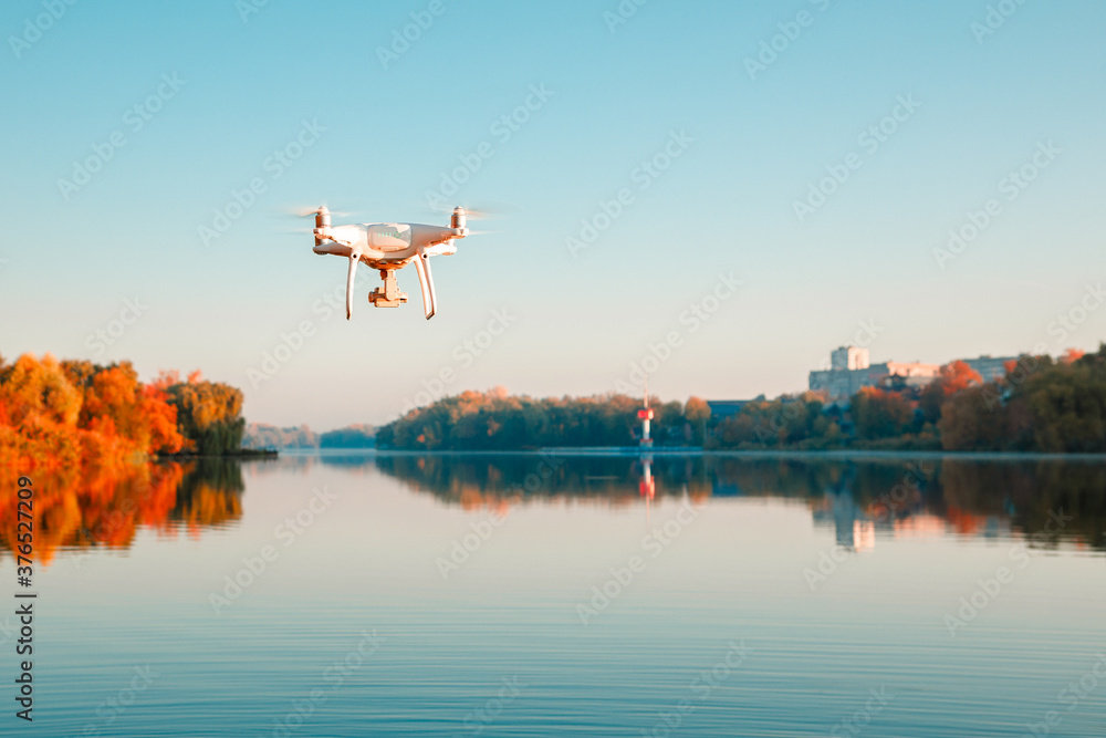 Fototapeta premium Drone copter with digital camera, blur river on autumn background