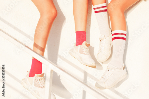girlfriends sitting on the wall - white sneakers close-up. Summer sports activities for teens, active kids lifestyle.